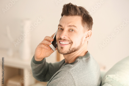 Young man talking on phone while working at home