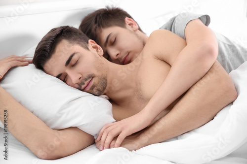 Young gay couple lying on bed at home