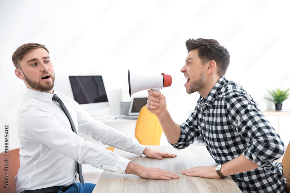 Angry boss with megaphone screaming at employee in office Angry boss with megaphone screaming at employee in office