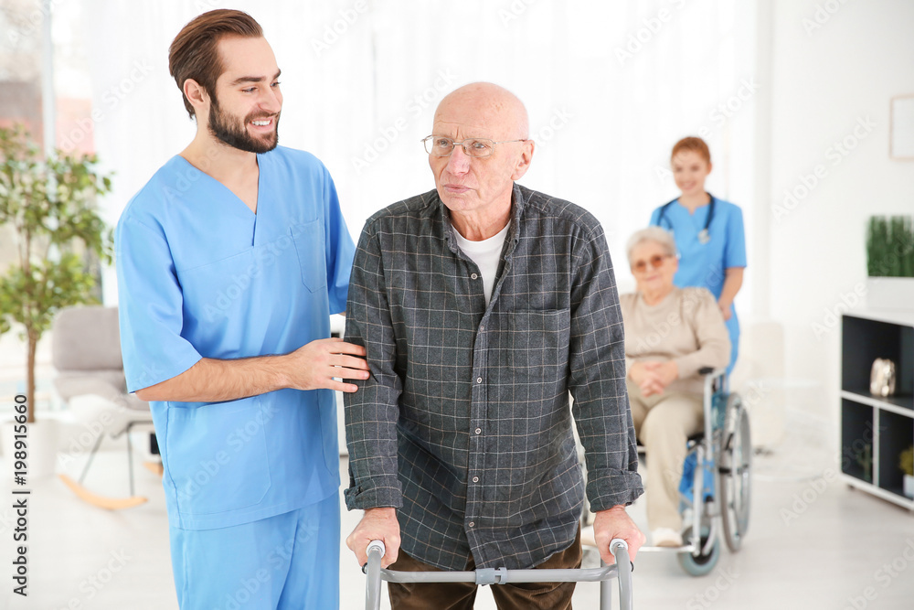 Fototapeta premium Senior man with walking frame and young caregiver at home