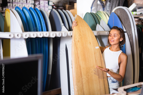 Photography Portrait of smiling woman with board for surfing in the shop