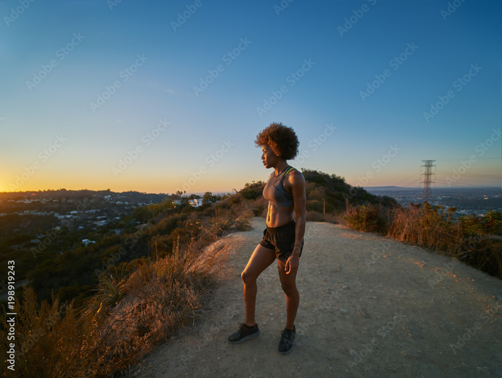 fit african american woman hiking runyon canyon stopping to see view of sunset