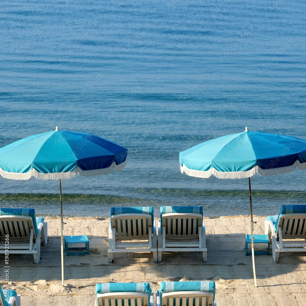 Beach hotel resort scene umbrella lounger chair calm clear blue sea summer holiday vacation location photo square format