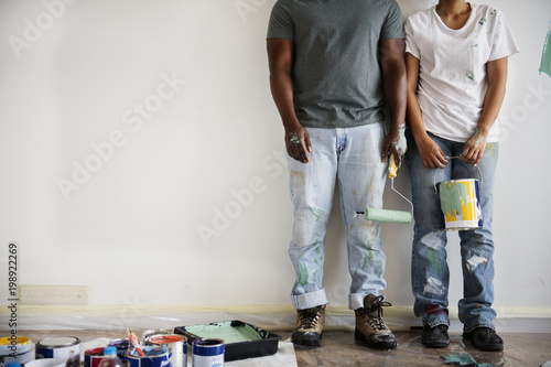 Couple painting house wall