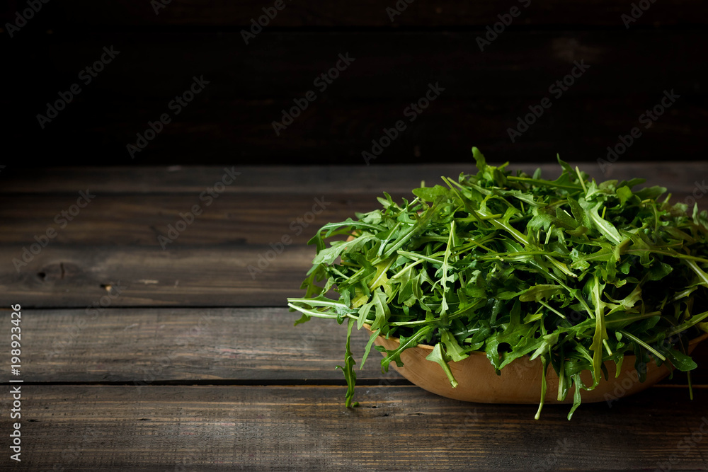 Fresh rucola with water droplets on a dark rustic background Fresh rucola with water droplets on a dark rustic background