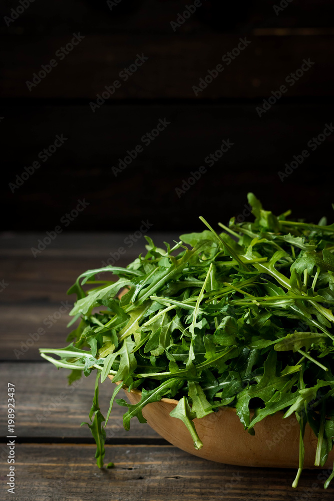 Fresh rucola with water droplets on a dark rustic background Fresh rucola with water droplets on a dark rustic background