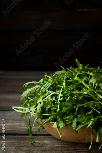 Fresh rucola with water droplets on a dark rustic background