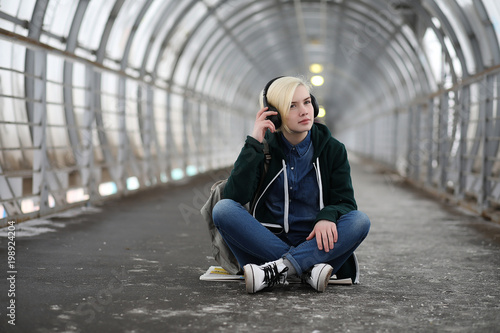 Young girl listens to music in big headphones in the subway
