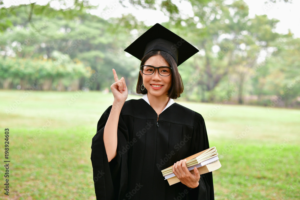 Graduation Concept. Graduated students on graduation day. Asian students are smiling happily on the graduation day. Students wear graduation gowns in the garden Graduation Concept. Graduated students on graduation day. Asian students are smiling happily on the graduation day. Students wear graduation gowns in the garden