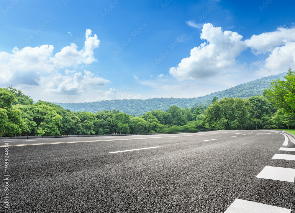 asphalt road and green forest with mountain landscape in summer