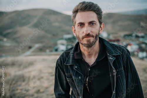 young man with  beard against  backdrop of  mountains