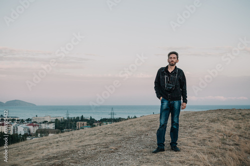 man stands on hill against background of sea and sky