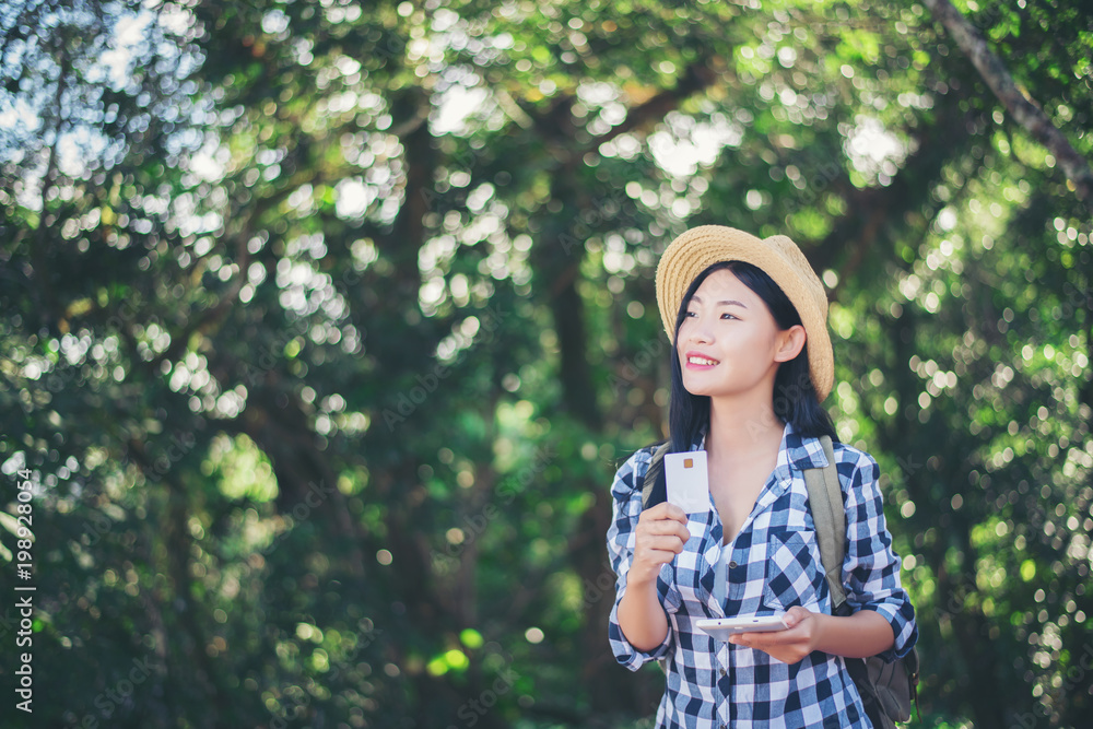 Young woman holding credit card and phone in the forest Young woman holding credit card and phone in the forest