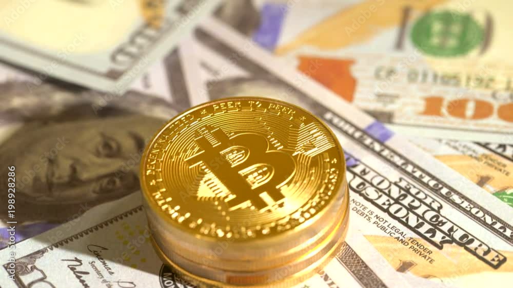 Bitcoin coins rotating on a pile of 100 dollar bills
