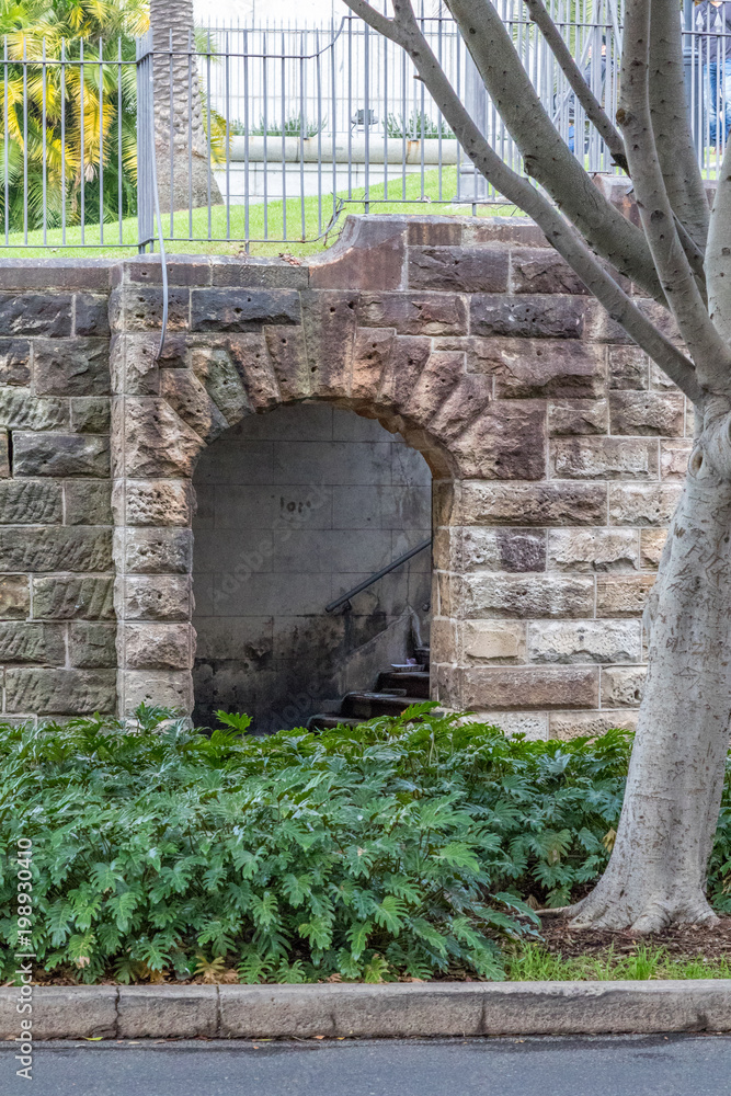 Fototapeta premium Arched sandstone entrance leading to stairs in city park