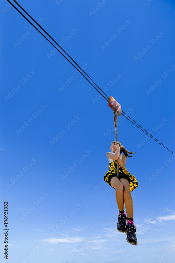 青空をバックにジップラインを滑る女の子 青空をバックにジップラインを滑る女の子