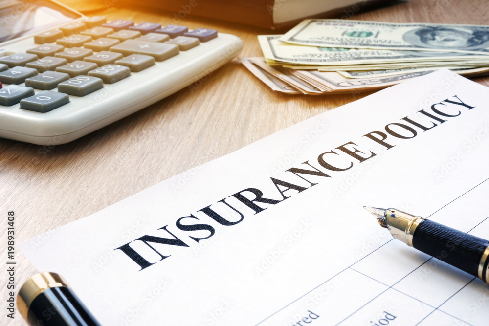 Insurance policy and dollar bills on an office desk. Insurance policy and dollar bills on an office desk.