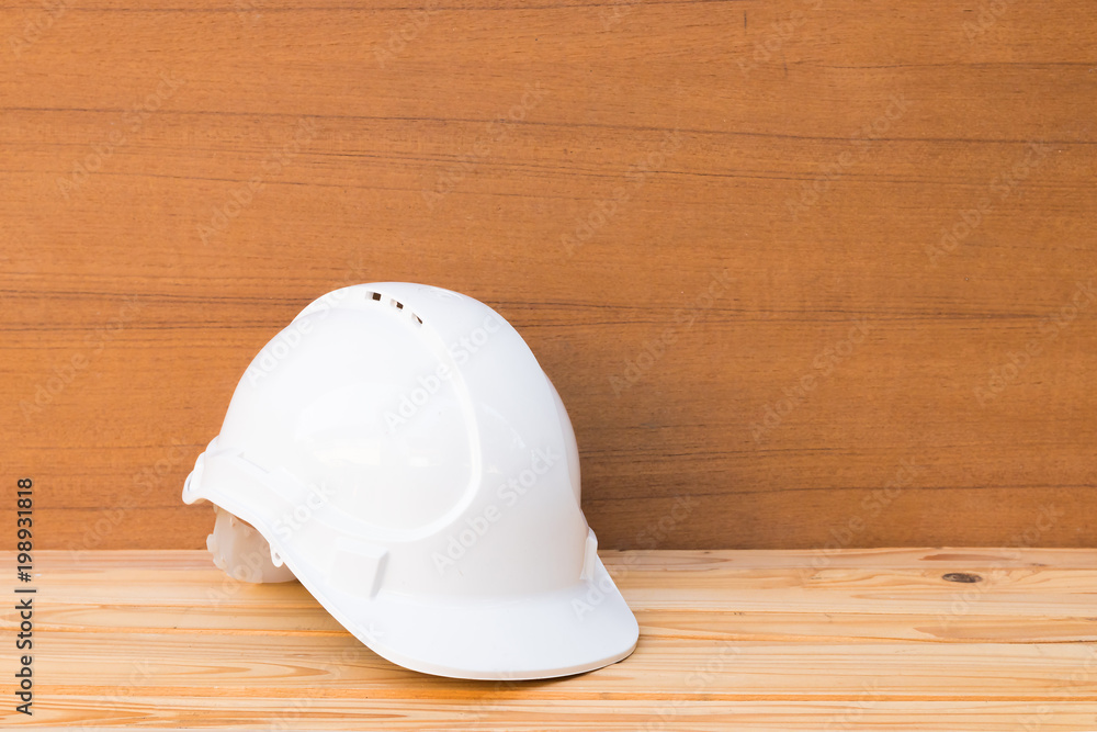 white safety helmet plastic construction of engineering on wood floor table background with copy space add text