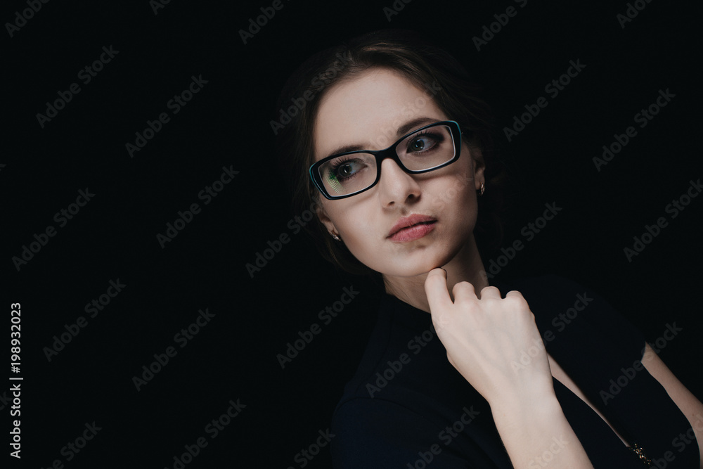 Close-up portrait of confident beautiful young business woman standing in office on black background Close-up portrait of confident beautiful young business woman standing in office on black background