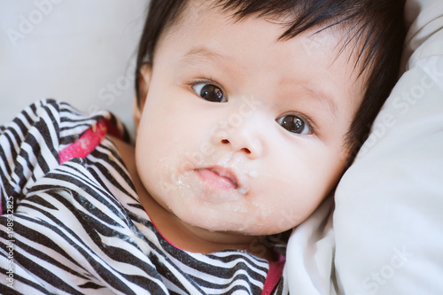 Portrait of cute asian baby girl looking at camera with dirty mouth after her meal