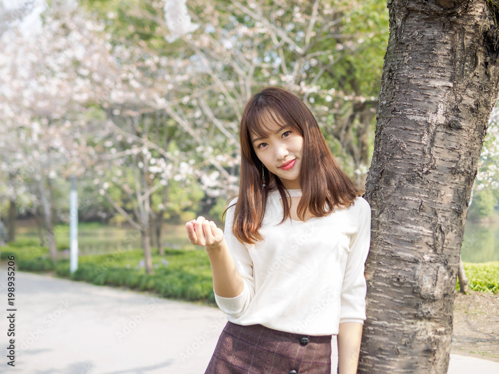 Outdoor portrait of beautiful young Chinese girl smiling among blossom cherry tree brunch in spring garden, beauty, summer, emotion, expression and people concept. Outdoor portrait of beautiful young Chinese girl smiling among blossom cherry tree brunch in spring garden, beauty, summer, emotion, expression and people concept.