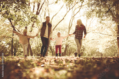 Bild auf Leinwand Cheerful family walking trough park together with open arms.