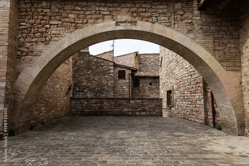 View of a small square in Spello town (Umbria, Italy), with an arch filling almost the whole image