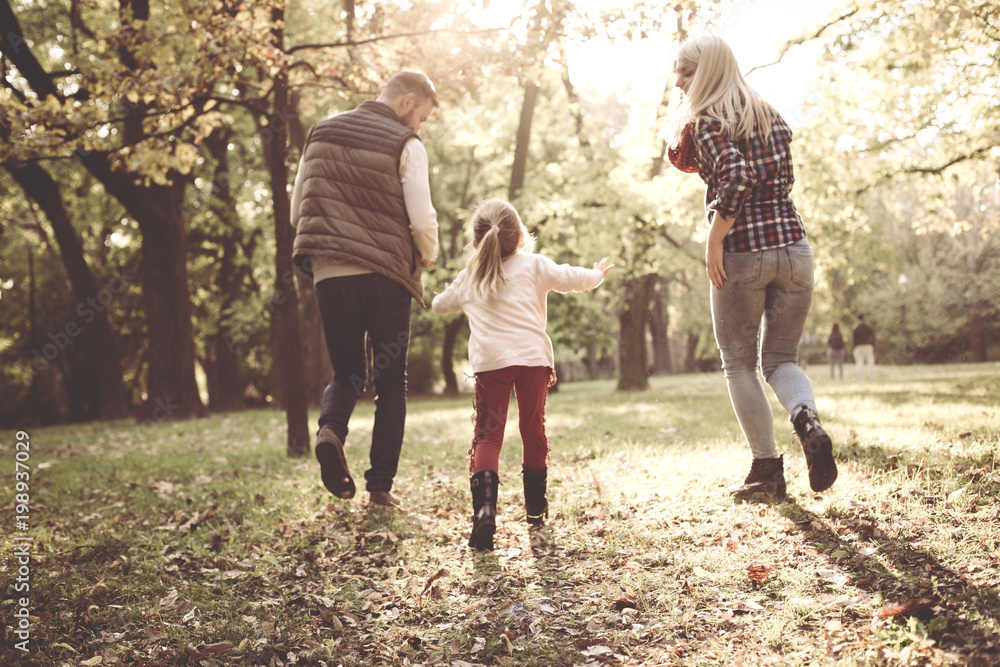 Fototapeta premium Happy parents and their little girl playing on meadow together.