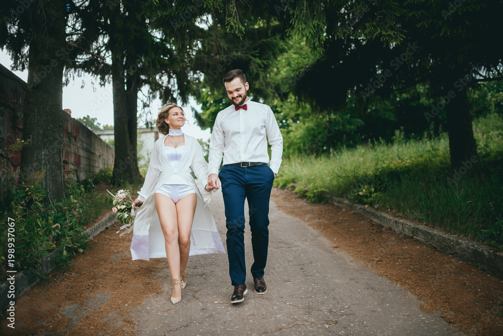 Fototapeta premium Happy newlywed couple on a walk in old European town street, gorgeous bride in white wedding dress together with handsome groom
