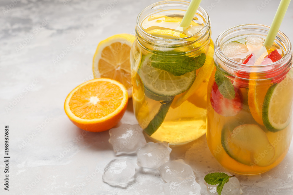 Fruit ice tea and ginger herbal ice tea with mint in a glass jars, white background, copy space. Summer refreshing drink concept. Fruit ice tea and ginger herbal ice tea with mint in a glass jars, white background, copy space. Summer refreshing drink concept.