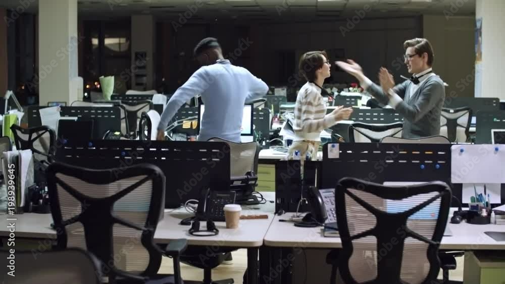 PAN of laughing call centre operators dancing in office after hours PAN of laughing call centre operators dancing in office after hours