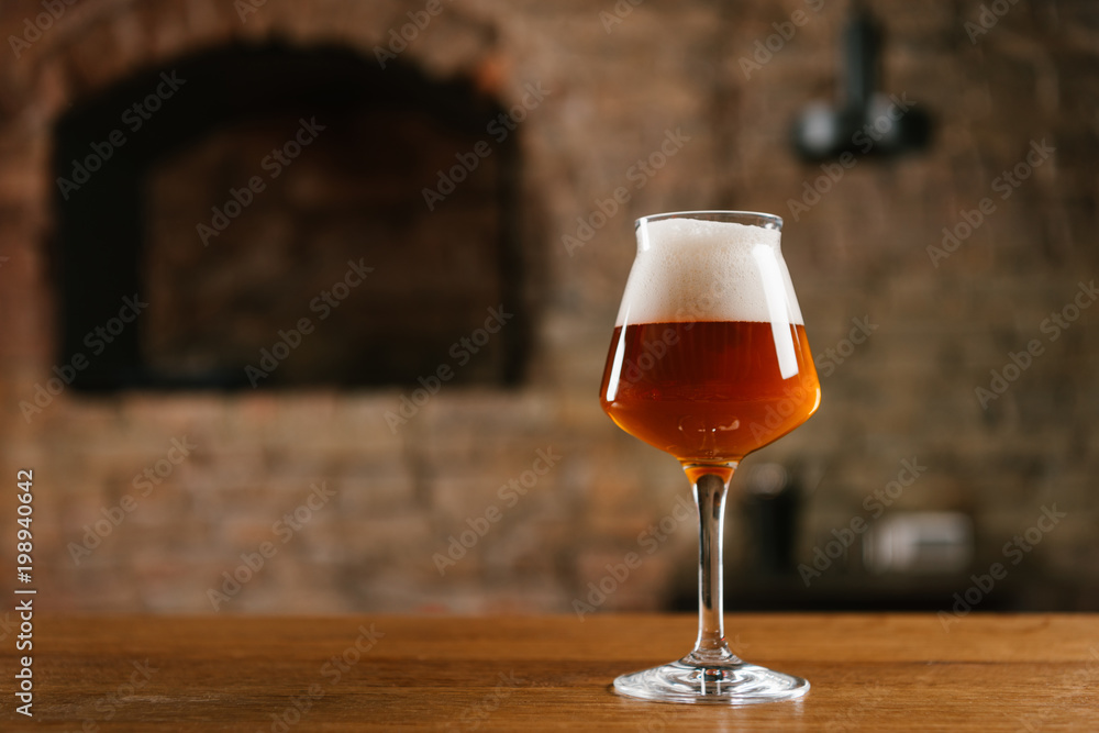close-up view of fresh cold beer in glass on wooden table in bar