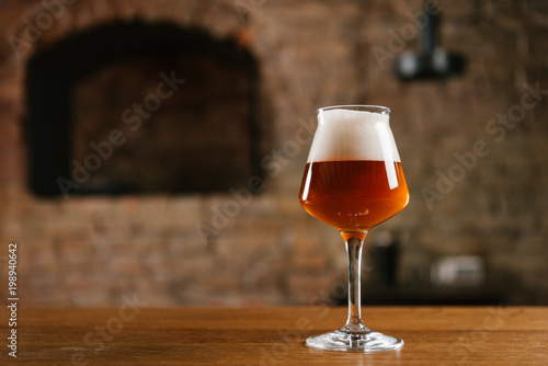 close-up view of fresh cold beer in glass on wooden table in bar
