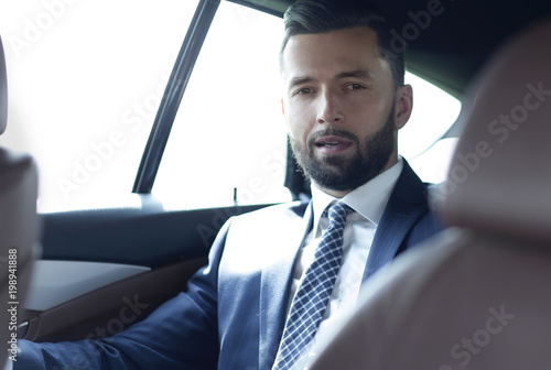 handsome bearded businessman sitting on back seat of car © ASDF