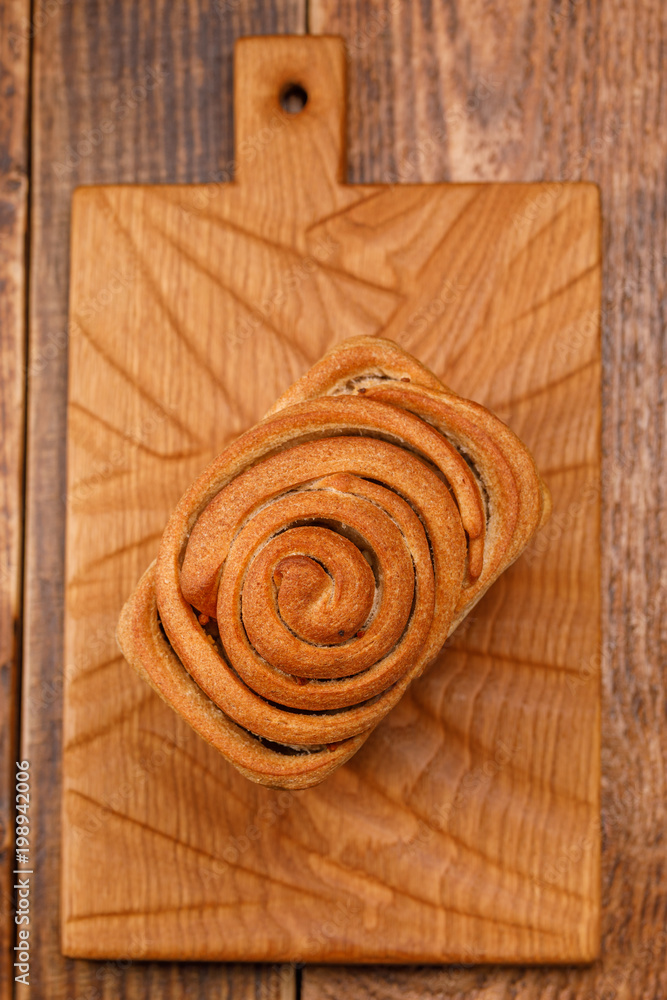 Beautiful homemade bread on a textured wooden board. A beautiful combination of the color of a wooden background and bread. Top wiev.