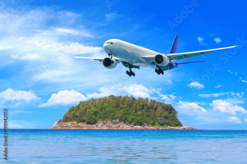 Passenger airplane flying above tropical beach in Phuket, Thailand. Amazing view of blue sea and golden sand.