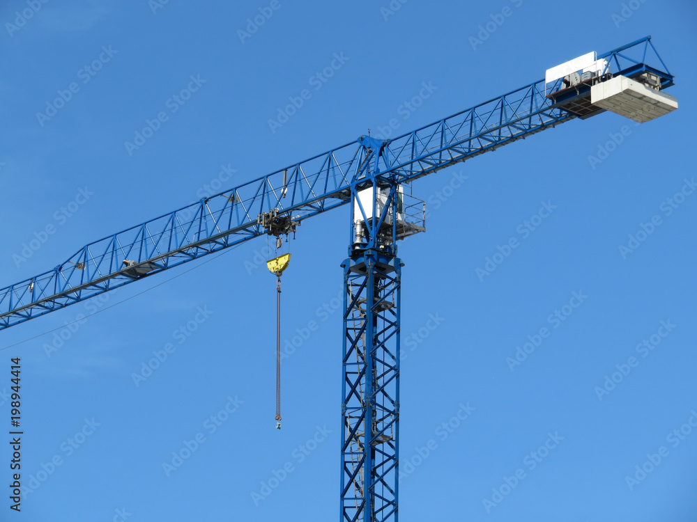Construction crane with lifting hook. Tower crane against the clear blue sky
