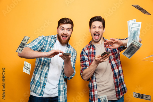 Portrait of a two happy young men scattering money photo