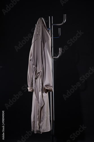 Obraz na plátně trench coat hanging on coat rack isolated on black