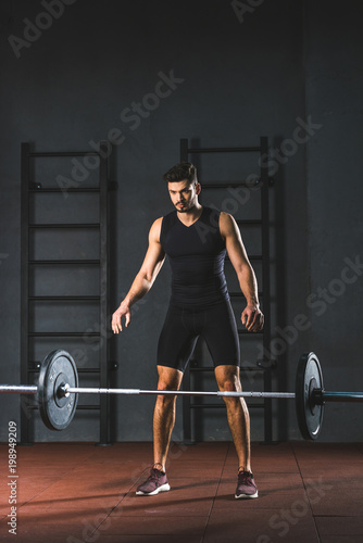 Young caucasian sportsman letting go barbell in sports hall