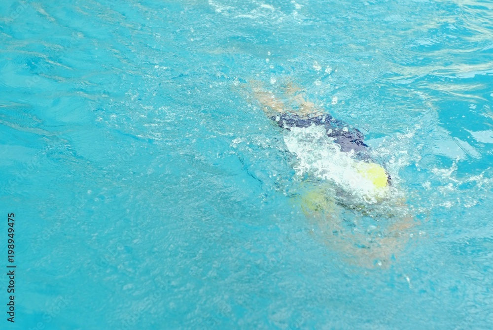 Motion image of child practicing swimming in a pool.