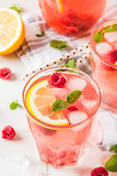 Summer refreshing drinks, fruit and berry raspberry mojito or lemonade with fresh mint, frozen raspberries, slices of lemon, ice, on a light background. copy space