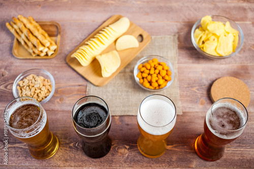 glasses of light and dark beer with assorted snacks on a wooden table background. bachelor party, pub, bar or degustation concept. top view, flat lay