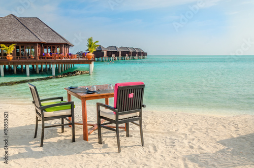 Table and chairs at restaurant at the background of water bungalows  Maldives island