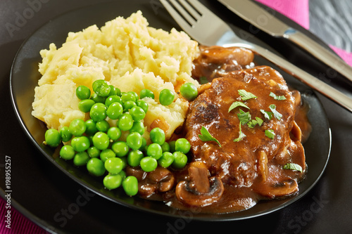 close-up of salisbury steaks with green peas