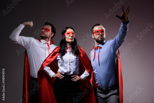 super businesspeople in masks and capes showing superpower isolated on grey photo