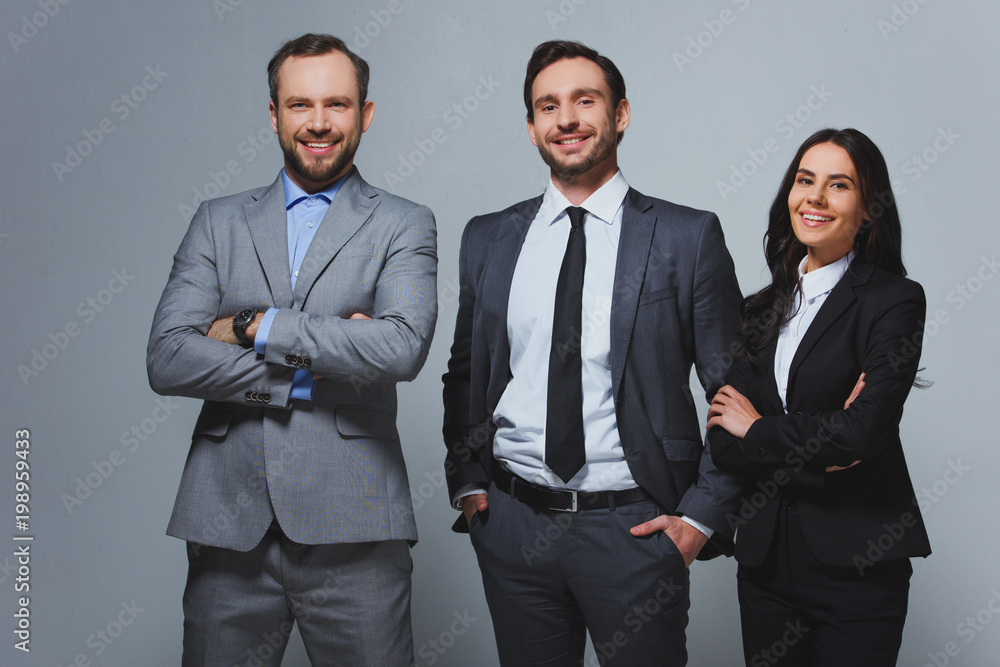smiling businesspeople looking at camera isolated on grey