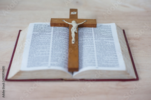 The wooden cross over opened bible on wooden table