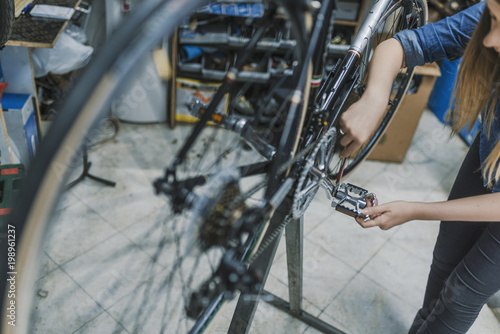Technician woman fixing bicycle in repair shop