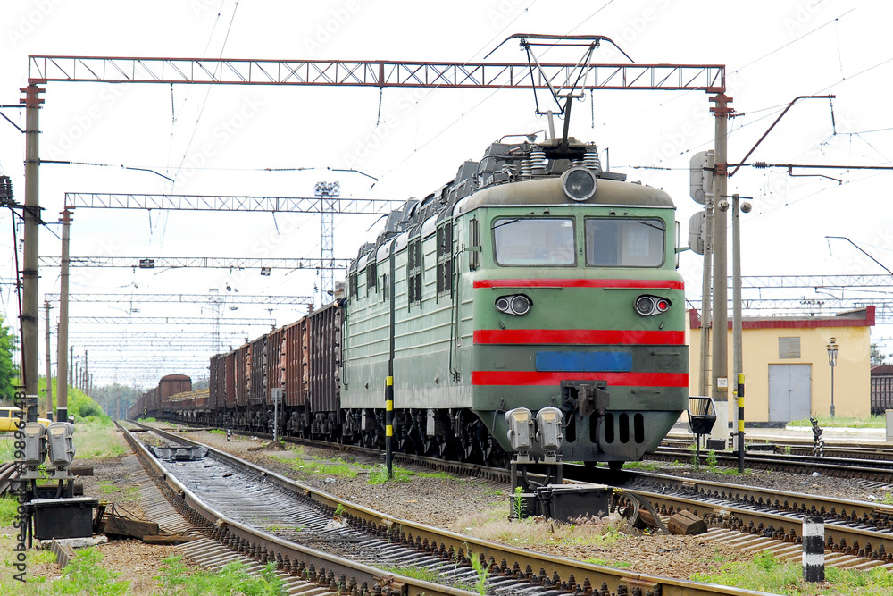 Electric locomotive of green color pulls freight cars